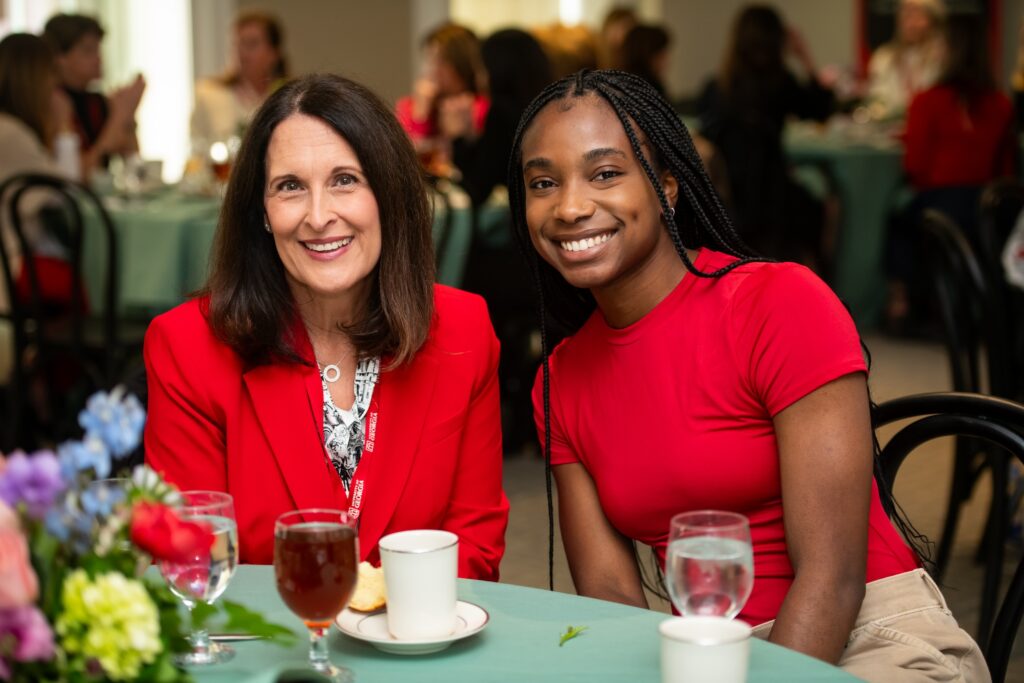 Samantha Crosby and Dami Odubola sit at a table at the Georgia Women Give spring event in UGA’s Moore-Rooker Hall.